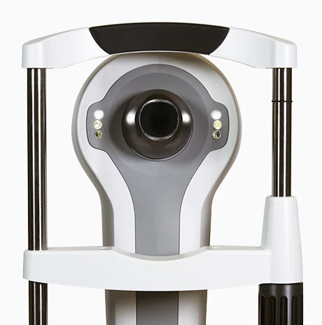 Close-Up Of A Nidek Medical Device, Possibly An Optometry Instrument, With A Circular Central Lens Flanked By Two Small Lights. The Device Features A White And Grey Color Scheme With Vertical Metal Supports On Each Side.