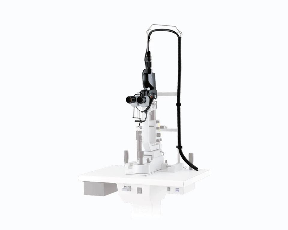 A Nidek Medical Slit Lamp Used For Eye Examinations Stands Mounted On A White Table With Control Knobs And Adjustable Components. An Attached Black Cable Extends From The Top Of The Lamp. The Background Is Light Gray.