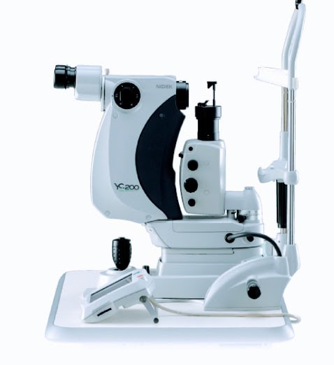The Nidek Ophthalmic Laser Device, Model Yc-200, Used For Eye Treatments, Features A Binocular Eyepiece, Control Buttons, Adjustment Knobs, And A Support Structure For Patient Chin And Forehead Rest. This Device Is Designed For Use On A Clinical Or Hospital Examination Table.