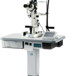 A Modern Nidek Ophthalmic Slit Lamp Biomicroscope On A Wheeled Stand With Various Attached Components, Including An Adjustable Binocular Microscope, Control Knobs, And An Integrated Light Source. A Foot Pedal Is Placed Nearby On The Floor.