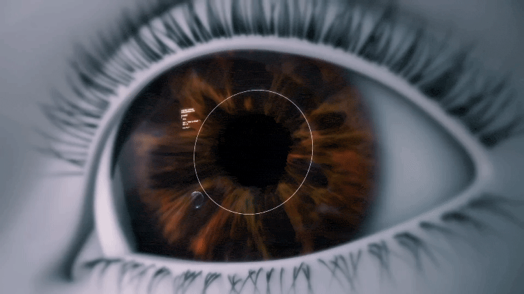 Close-Up Image Of A Human Eye With A Detailed Iris In Shades Of Brown And Amber. A Circle With Notches And Small White Markings Overlaps The Iris, Resembling A High-Tech Nidek Scanning Interface. Eyelashes Are Visible Around The Eye. The Image Has A Futuristic Feel.