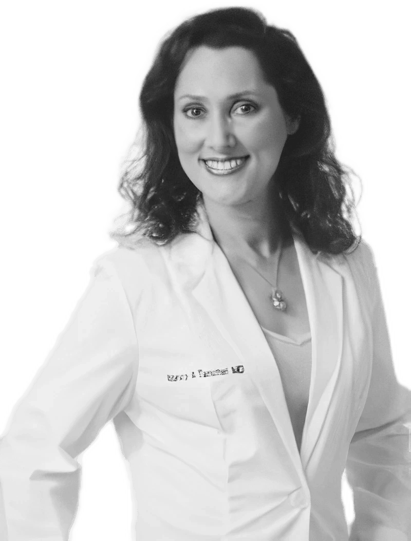 A Smiling Woman With Wavy Hair Is Wearing A White Lab Coat Over A Light-Colored Top. She Stands Confidently With One Hand On Her Hip, And &Quot;Md&Quot; Embroidered On Her Coat. The Image, In Striking Black And White, Subtly Hints At The Excellence Of Nidek'S Medical Innovation.